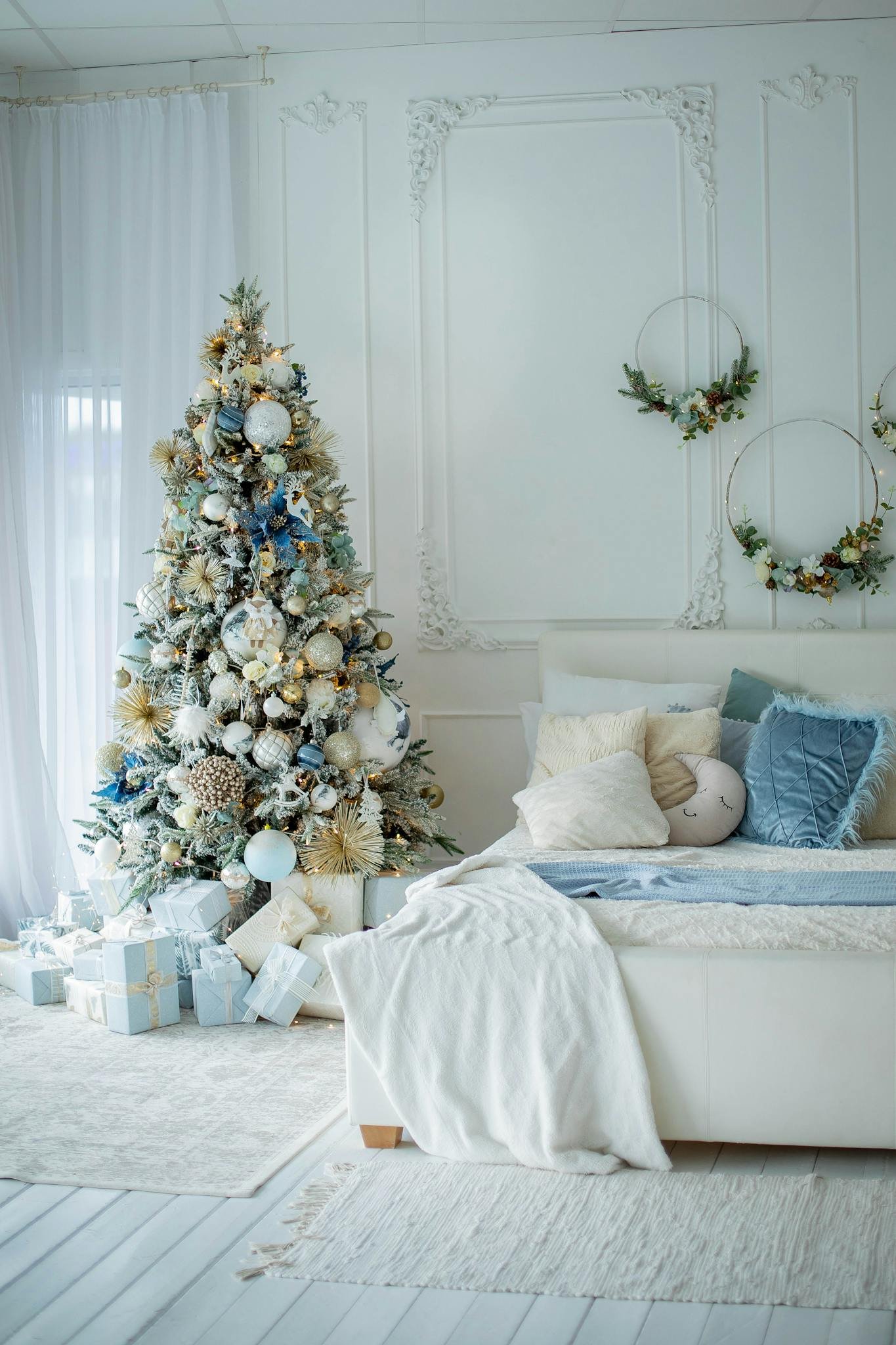 Luxurious bedroom with a white and blue themed Christmas tree and decorations, creating a festive atmosphere.